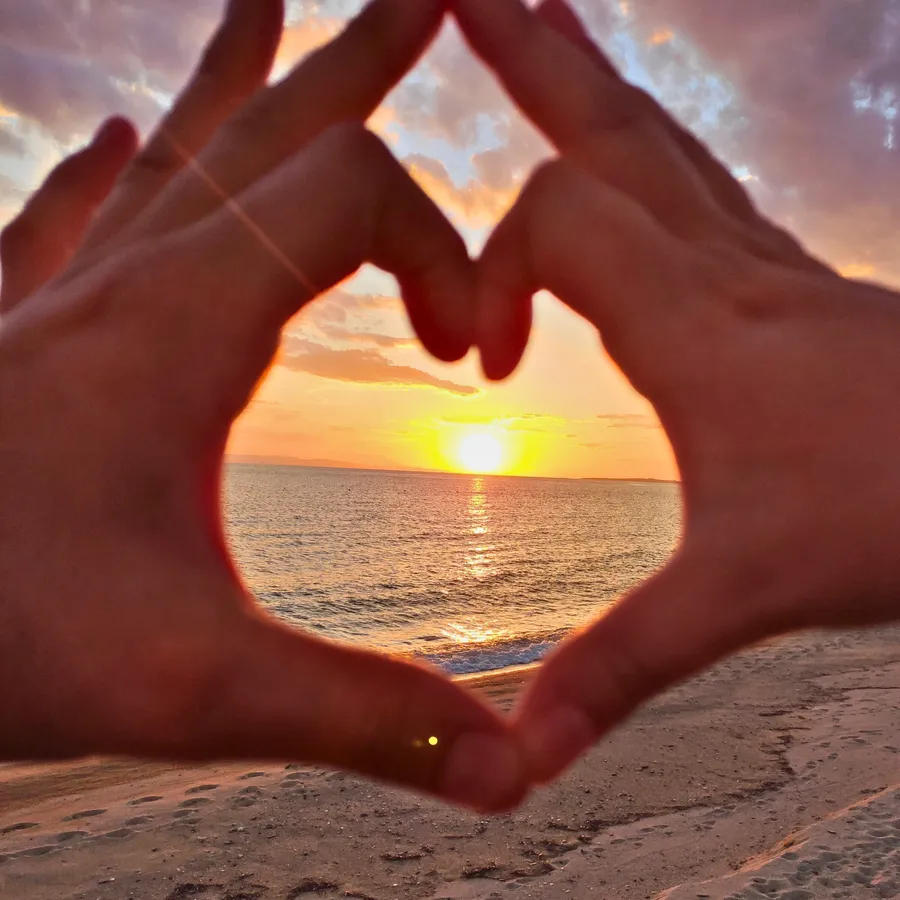 Hands forming a heart around the sunset on a Toroni beach, Halkidiki